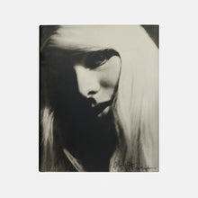 Black and white portrait of a woman with long hair, partially covering her face.